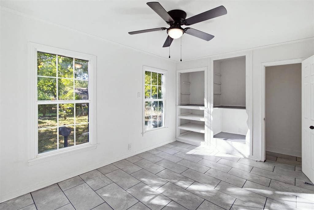 1105 Bell Drive, Greenville, TX 75401 Bright, light-filled room featuring tile flooring, multiple windows with natural light, ceiling fan with pull-chain controls, and direct access to adjacent spaces through French doors with integrated blinds