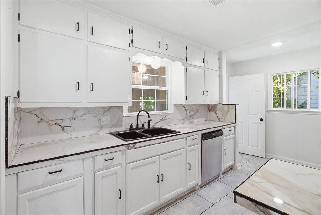 1105 Bell Drive, Greenville, TX 75401 Kitchen featuring white cabinetry, a double basin sink, stainless steel dishwasher, and marble-look countertops with a matching backsplash