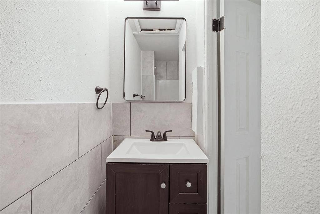 1105 Bell Drive, Greenville, TX 75401 Vanity with integrated sink, dark wood-finish cabinetry, and dark bronze-finish faucet
