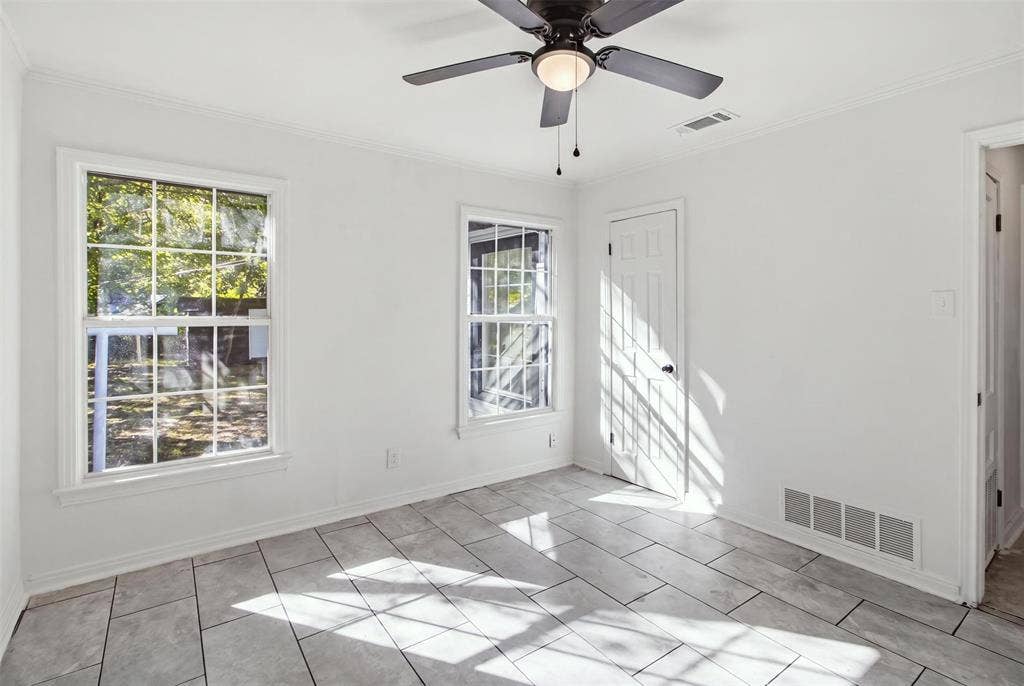 1105 Bell Drive, Greenville, TX 75401 White painted interior with two grid-pattern windows, a ceiling fan with integrated lighting, and light-toned tile flooring