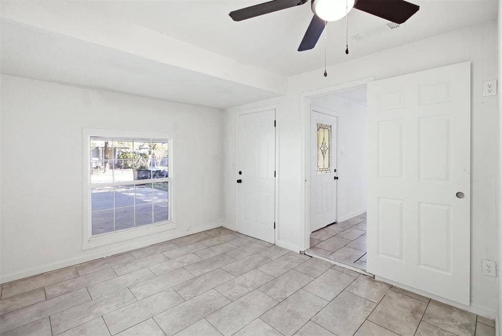 1105 Bell Drive, Greenville, TX 75401 Tile flooring, ceiling fan, white paneled doors, window with grid, and a door with decorative glass