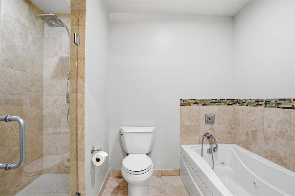 500 Throckmorton Street, #1605, Fort Worth, TX 76102 Tiled shower enclosure with a rainfall shower head, glass shower door, and a built-in tub with jets