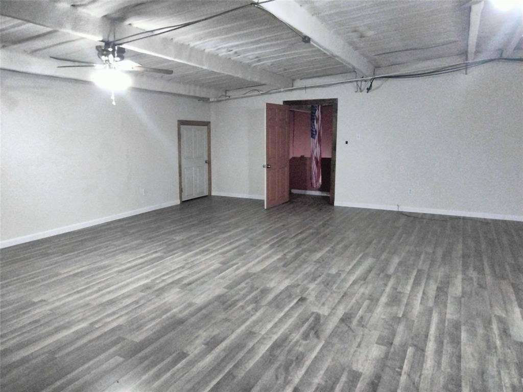 10424 County Road 1099, Princeton, TX 75407 Spacious room featuring wood-finish flooring, a ceiling fan with integrated lighting, and exposed ceiling beams
