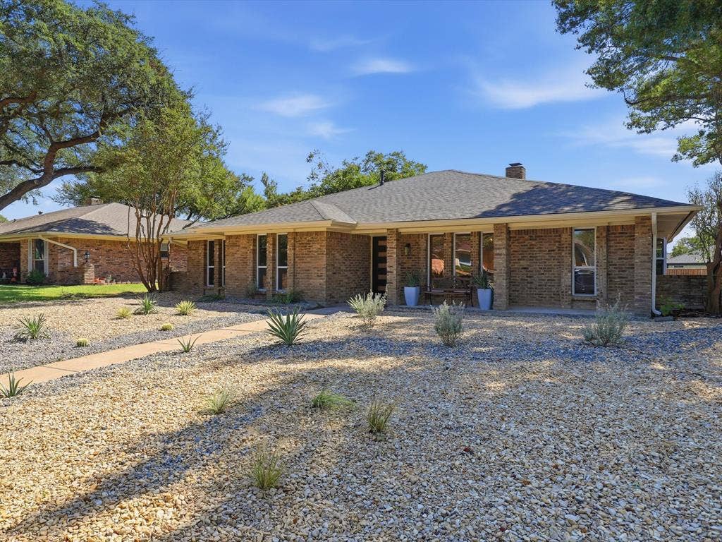 2500 Teakwood Lane, Plano, TX 75075 Brick exterior with a gray shingle roof, complemented by a gravel and xeriscape front yard featuring a paved walkway