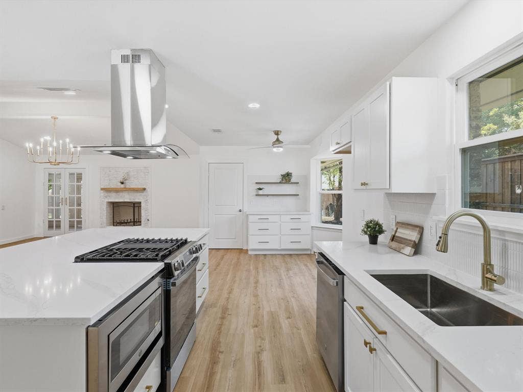 2500 Teakwood Lane, Plano, TX 75075 Spacious kitchen featuring an island with built-in range, stainless steel appliances, white cabinetry, and wood-finish flooring