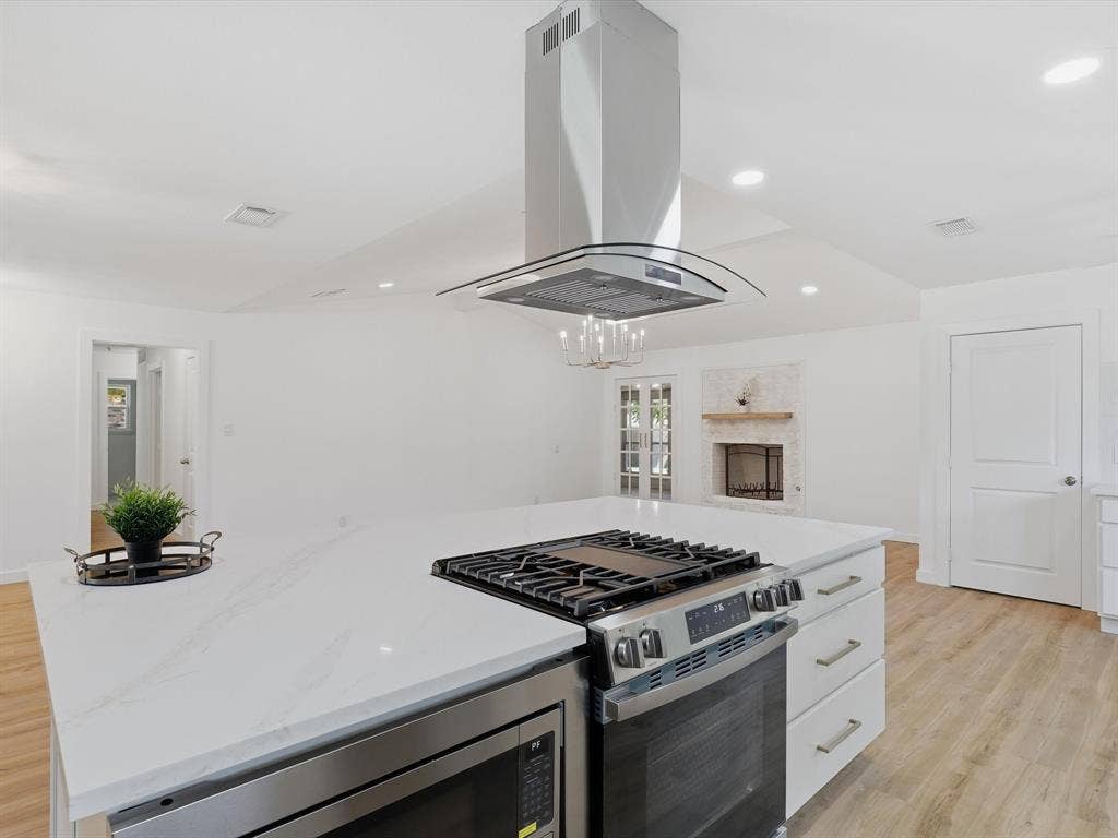 2500 Teakwood Lane, Plano, TX 75075 Kitchen island with a built-in stainless steel range, white countertop, and stainless steel microwave