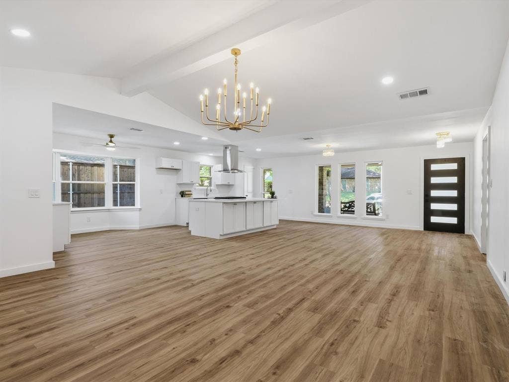 2500 Teakwood Lane, Plano, TX 75075 Vaulted ceilings, wood-finish flooring, central island kitchen, modern black entry door, and multiple windows
