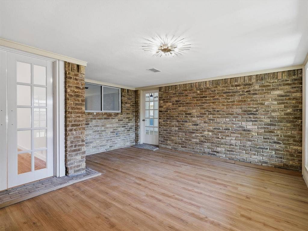 2500 Teakwood Lane, Plano, TX 75075 Wood-finish flooring, exposed brick wall, white French doors, and recessed lighting
