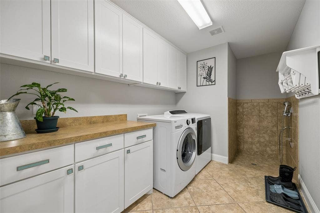 Tons of cabinets in this laundry with dogwash that's connected to the primary closet