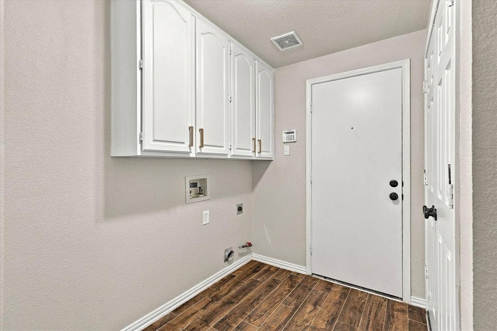 2412 Clearwood Lane, Flower Mound, TX 75028 FUNCTIONALITY WITH A TOUCH OF STYLE! Beautiful white overhead cabinetry, rich wood-look tile flooring, and a dedicated laundry space make everyday organization effortless.
