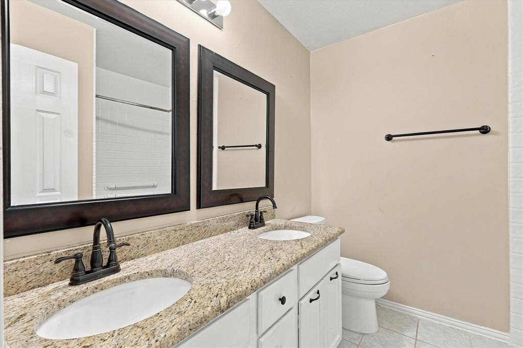 2412 Clearwood Lane, Flower Mound, TX 75028 CLASSIC ELEGANCE MEETS EVERYDAY CONVENIENCE! Beautiful granite countertops, dual sinks, rich dark-framed mirrors, and contrasting fixtures create a polished bathroom with plenty of space for daily routines.
