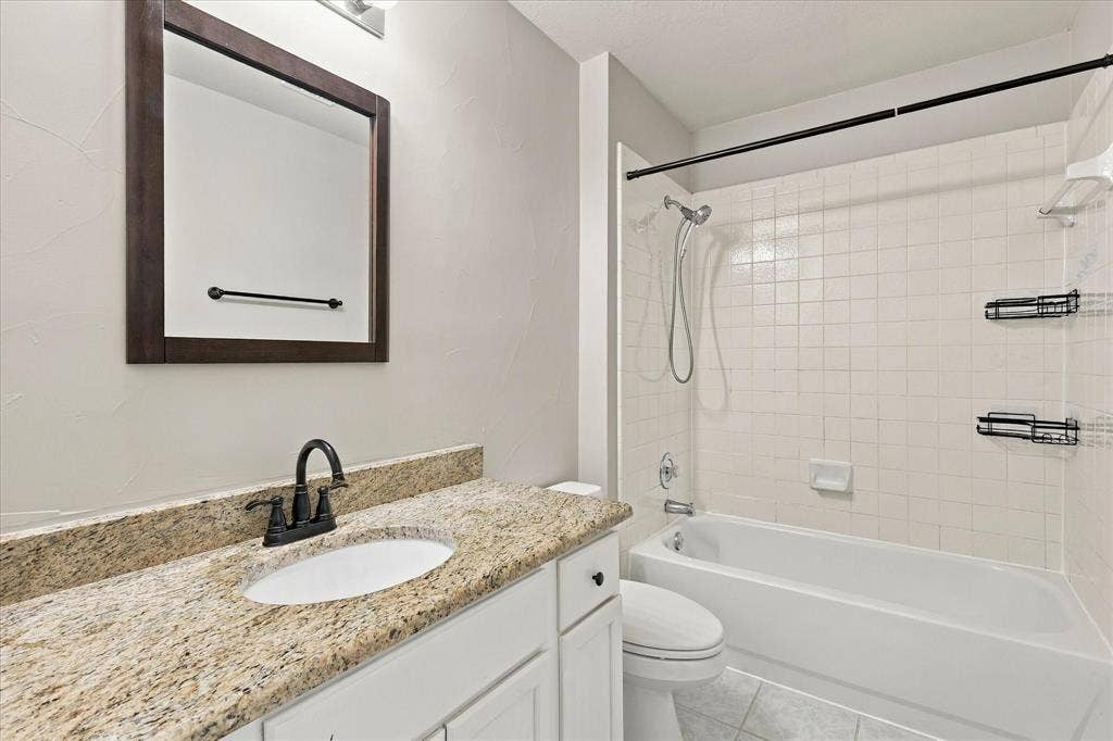 2412 Clearwood Lane, Flower Mound, TX 75028 CLASSIC ELEGANCE & EVERYDAY COMFORT! Gorgeous granite countertops, rich dark fixtures, a beautifully framed mirror, and a crisp white tiled tub and shower create an inviting bathroom with timeless appeal.