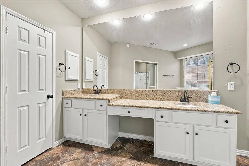2412 Clearwood Lane, Flower Mound, TX 75028 EVERYDAY LUXURY, BEAUTIFULLY DESIGNED! An expansive dual-sink vanity features gorgeous granite countertops, a generous wall-to-wall mirror, abundant cabinet storage, and a dedicated seated vanity area.