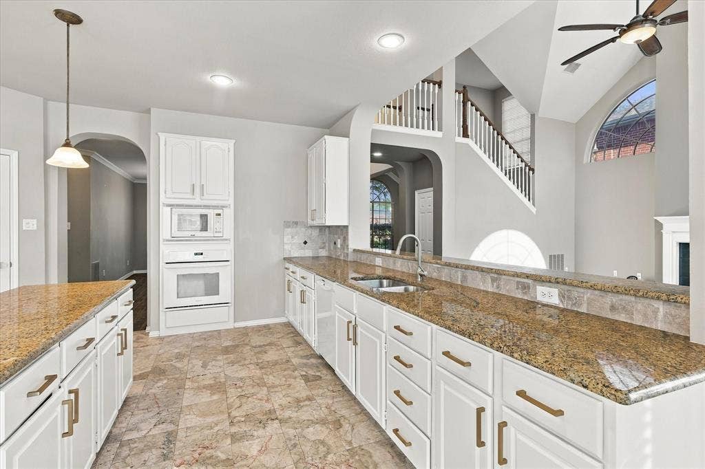 2412 Clearwood Lane, Flower Mound, TX 75028 EFFORTLESS ENTERTAINING STARTS HERE! A spacious kitchen with granite countertops, generous cabinetry, and a convenient breakfast bar opens to the home's stunning two-story living area, creating an inviting atmosphere for memorable gatherings.