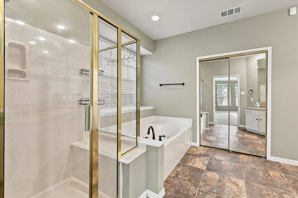 2412 Clearwood Lane, Flower Mound, TX 75028 YOUR PERSONAL SPA EXPERIENCE! Unwind in the luxurious soaking tub or refresh in the separate glass-enclosed shower. Beautiful tile flooring, abundant natural light, and classic finishes create an inviting space for relaxation.
