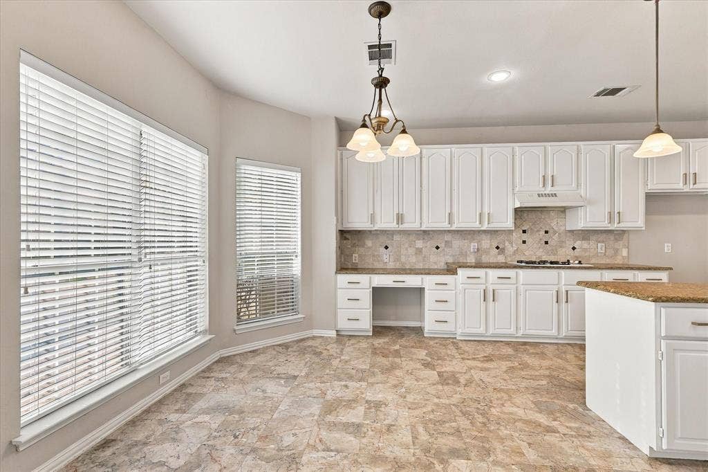 2412 Clearwood Lane, Flower Mound, TX 75028 A BRIGHT AND INVITING HEART OF THE HOME! Beautiful white cabinetry with a built in desk, generous countertops, decorative tile backsplash, and a sun-filled breakfast area create a welcoming kitchen with wonderful space for cooking, gathering, and everyday enjoyment.
