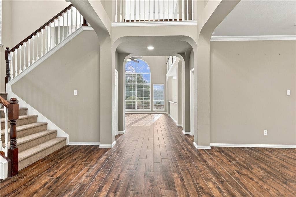 2412 Clearwood Lane, Flower Mound, TX 75028 GRAND DESIGN MEETS TIMELESS STYLE! A beautiful staircase, open second-story balcony, graceful archways, and rich wood-look tile floors showcase the home's exceptional architectural character. A light-filled passageway offers a captivating glimpse into the impressive living spaces beyond.