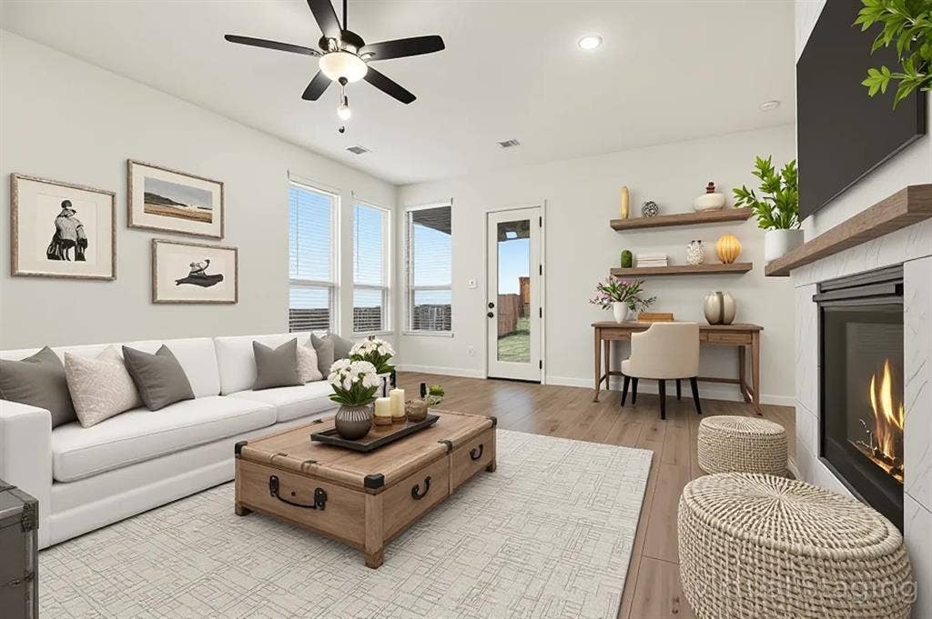 Fireplace with stone-style surround and wood mantel, wood-finish flooring, recessed lighting, ceiling fan, and floating wall shelves
