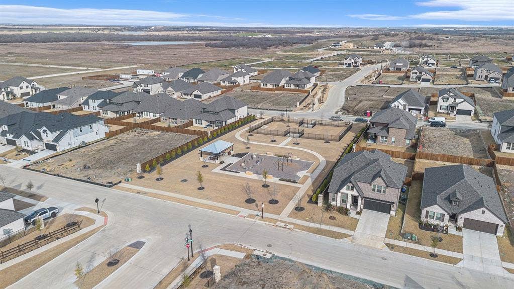 Aerial view of neighborhood amenities featuring a covered pavilion, multi-use play structure, perimeter fencing, and concrete pathways