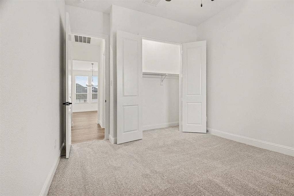Neutral-toned wall-to-wall carpeting, two-panel interior doors, built-in closet with wire shelving, and overhead ceiling fan