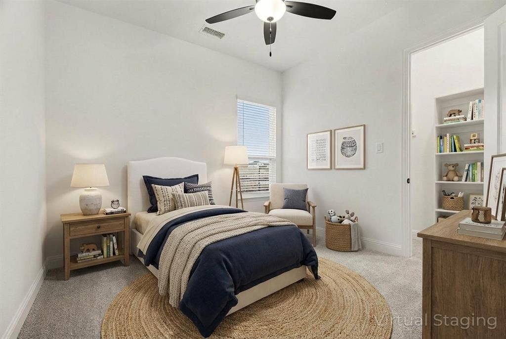 Neutral-toned carpet, ceiling fan with integrated lighting, window with horizontal blinds, and built-in shelving