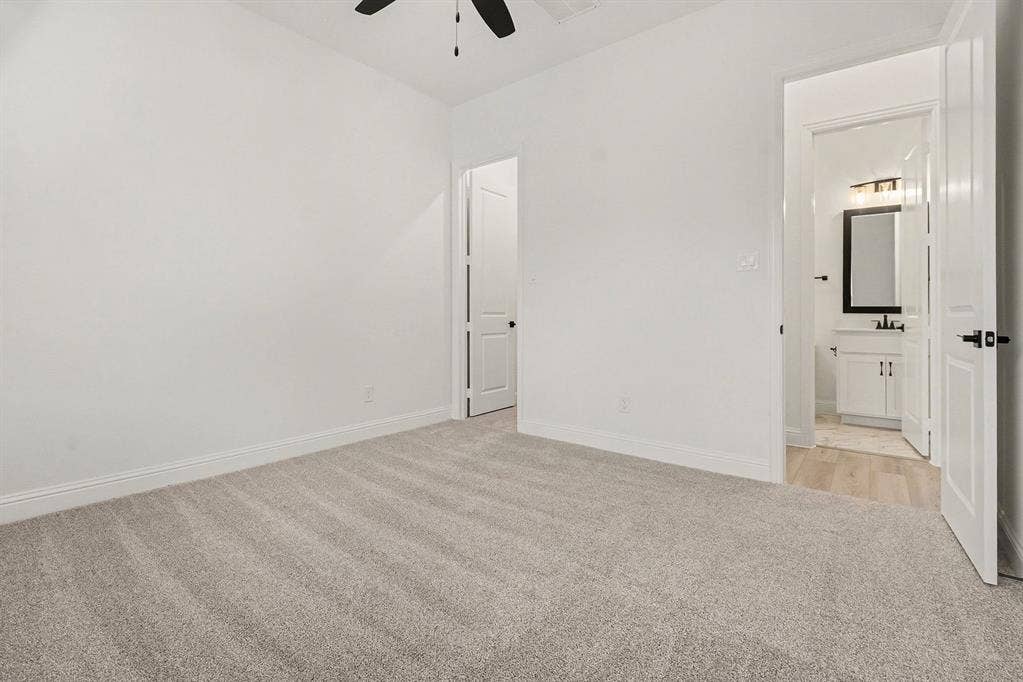 Interior room featuring neutral wall-to-wall carpeting, white walls, and a ceiling fan
