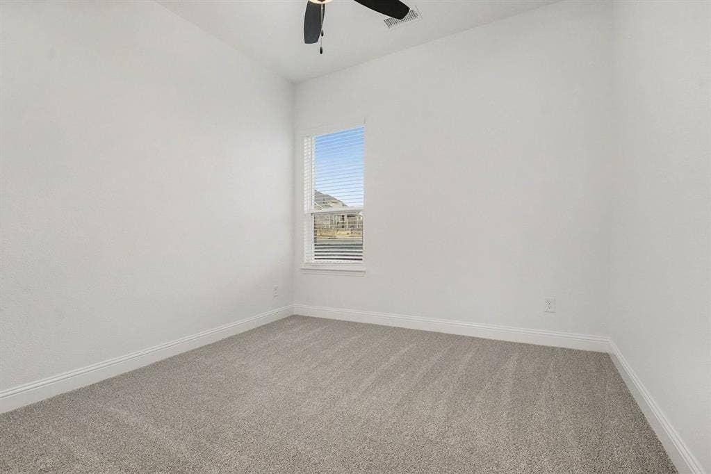 Neutral interior space featuring high ceilings, wall-to-wall carpeting, a single-hung window with blinds, and an integrated ceiling fan