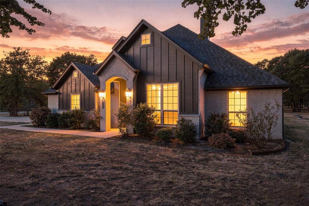 350 Timbers Circle, Poolville, TX 76487 Board and batten siding, brick exterior, arched entry, covered porch, and exterior lighting