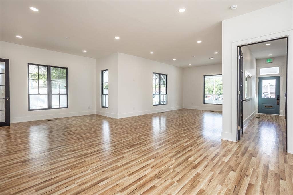 Open floor plan featuring wood-finish flooring, recessed lighting, multi-pane windows with dark frames, and neutral interior paint