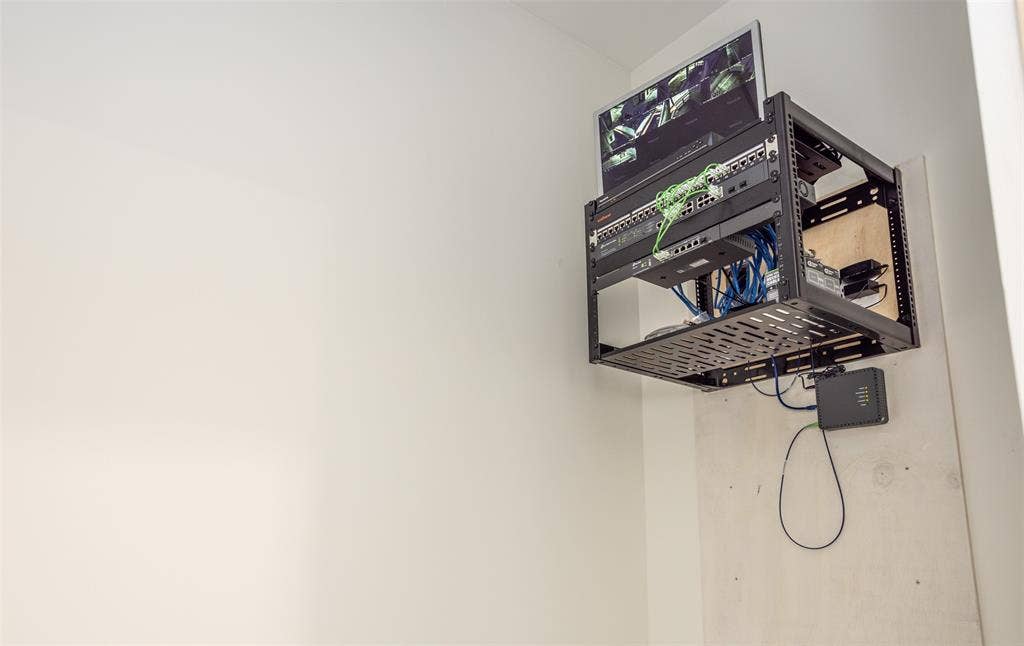 Wall-mounted server rack featuring organized networking hardware and an integrated monitor mount