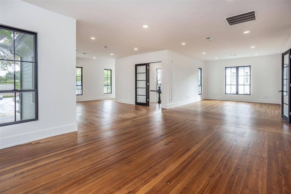 Open-concept interior featuring wood-finish flooring, recessed lighting, multi-pane windows with dark frames, and interior doors with glass paneling