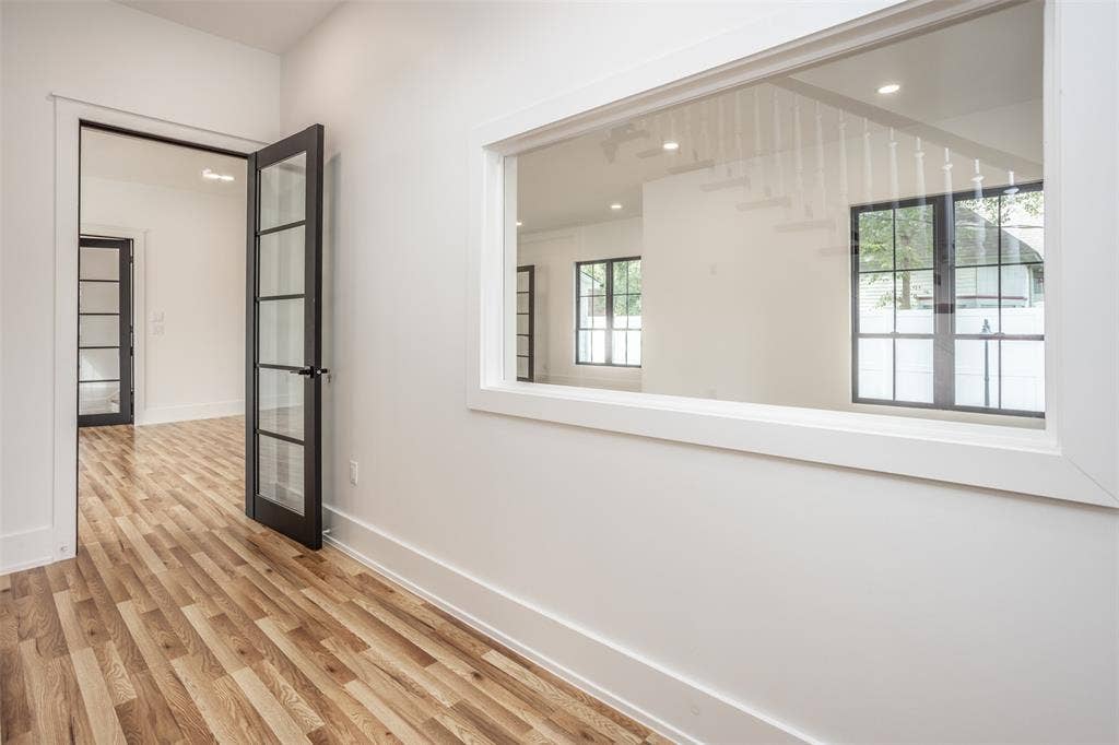 Interior space featuring wood-finish flooring, dark-framed glass paneled doors, and an expansive window with white trim casing
