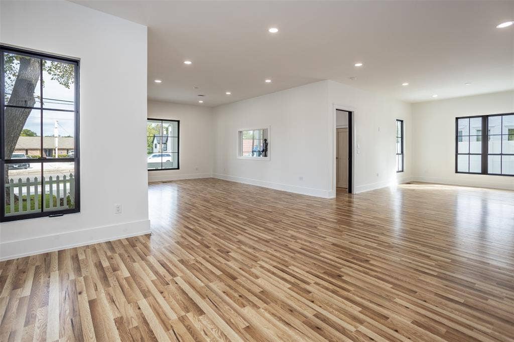 Open floor plan featuring wood-finish flooring, recessed lighting, and expansive windows with black frames