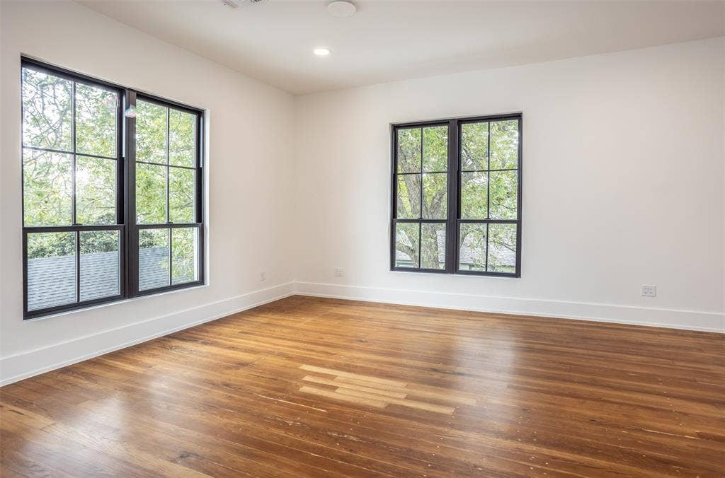 Spacious interior featuring wood-finish flooring, recessed lighting, and multiple oversized windows with dark mullions