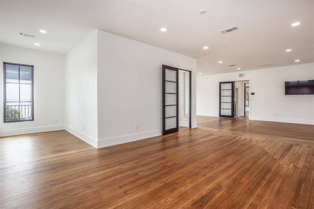 Wood-finish flooring, recessed lighting, and multi-pane dark-trimmed glass doors