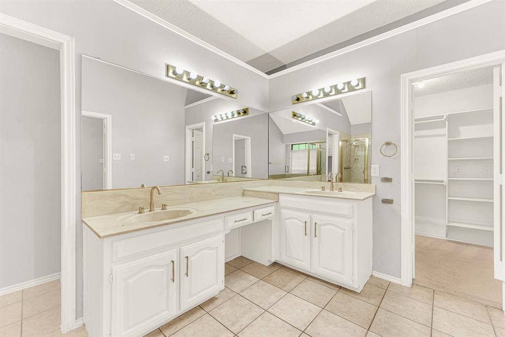 An L-shaped double vanity offers generous counter space while connecting directly to a spacious walk-in closet. Imagine easily selecting your daily outfit from the organized storage just steps away.