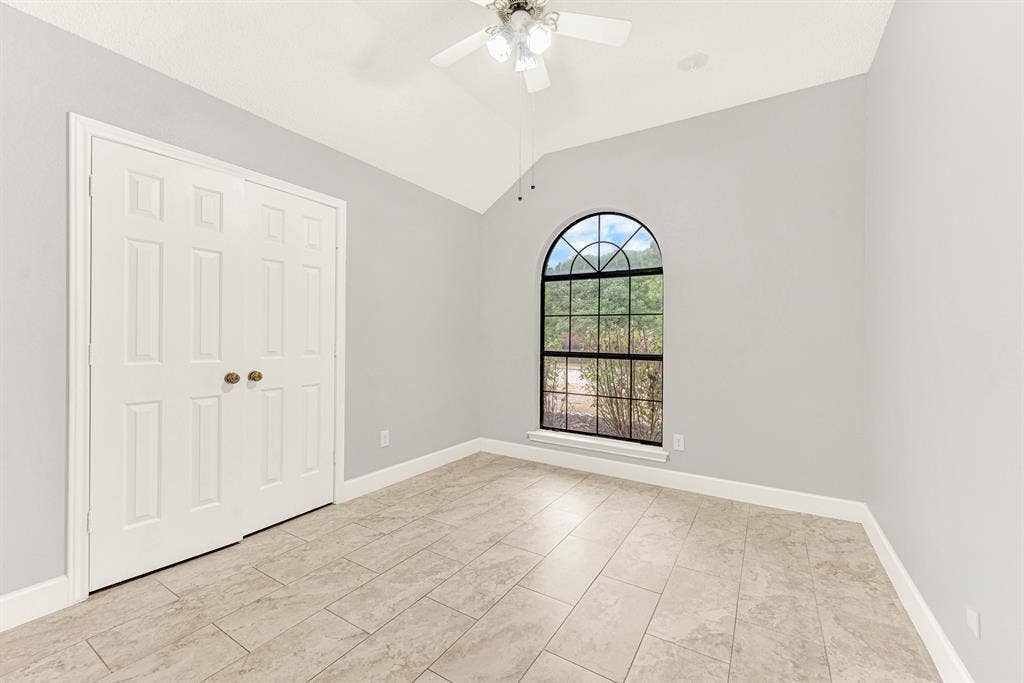 A grand arched window serves as a striking centerpiece, pouring natural daylight across the clean tiled floor. Imagine welcoming out-of-town loved ones into a bright, restful sanctuary where they can easily unpack and settle in