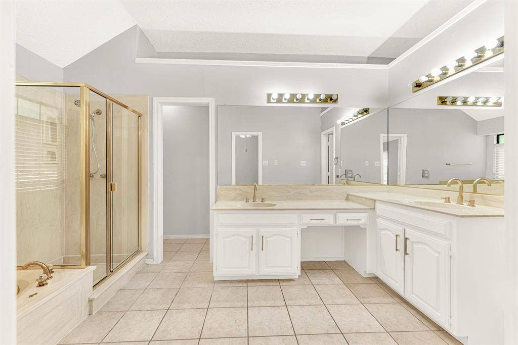 Warm brass accents frame the glass shower enclosure, adding classic detail alongside expansive vanity mirrors. Visualize your unhurried morning routine, enjoying glowing theatrical lighting as you get ready