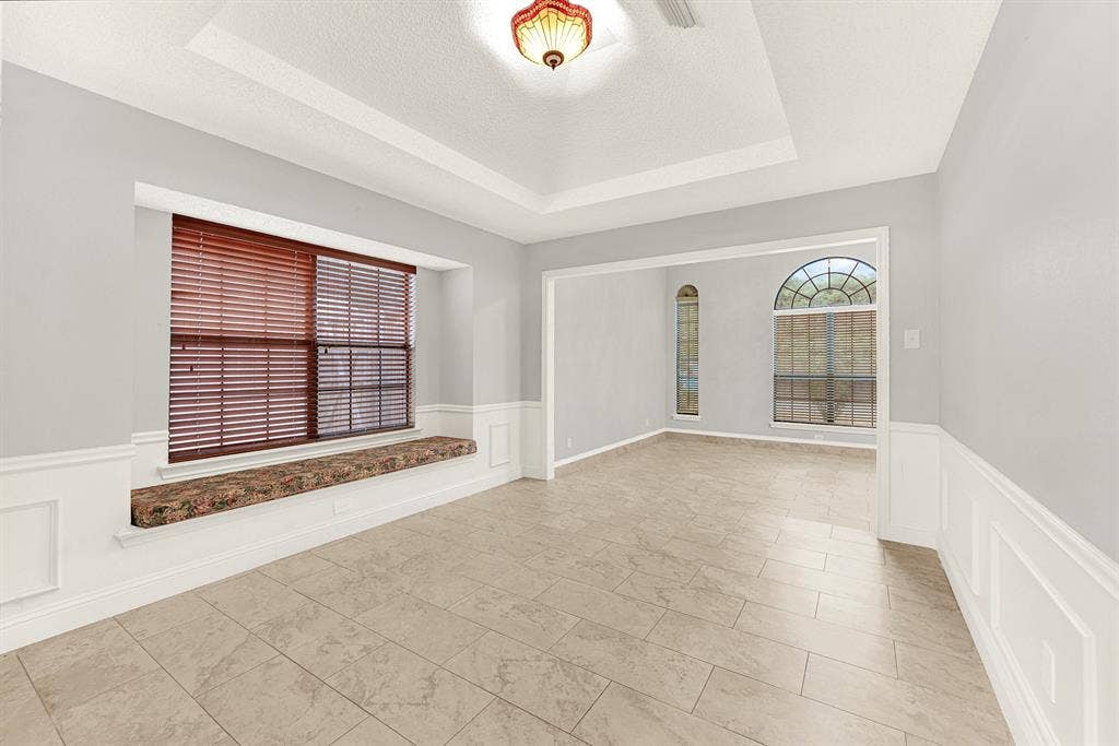Classic wainscoting frames the room while a built-in window nook bathes the surrounding walls in bright daylight. Imagine curling up on a quiet afternoon to read your favorite book beside the sunlit glass.