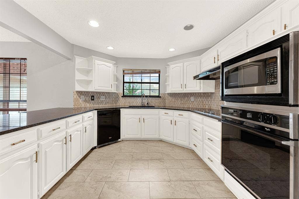A patterned tile backsplash wraps seamlessly behind crisp white cabinetry, balancing texture with a clean, airy feel. Picture baking holiday treats while warm aromas fill every corner of this inviting layout.