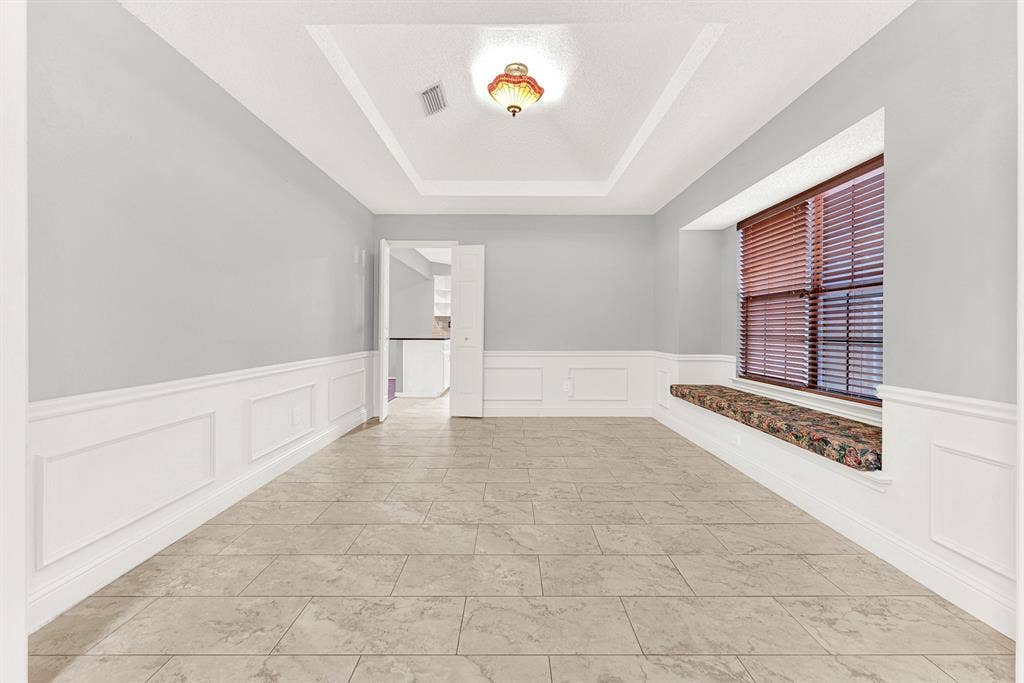 An elegant recessed tray ceiling draws the eye upward, catching soft glow from the central light fixture. Picture hosting intimate dinner parties where warm conversations linger long after dessert is served