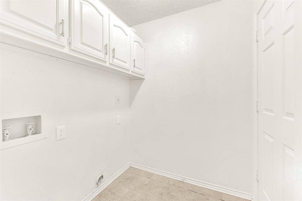 Upper white cabinetry maximizes vertical space, providing clean and concealed storage overhead. Visualize breeze-through laundry routines made effortlessly organized in this functional, clutter-free utility hub.