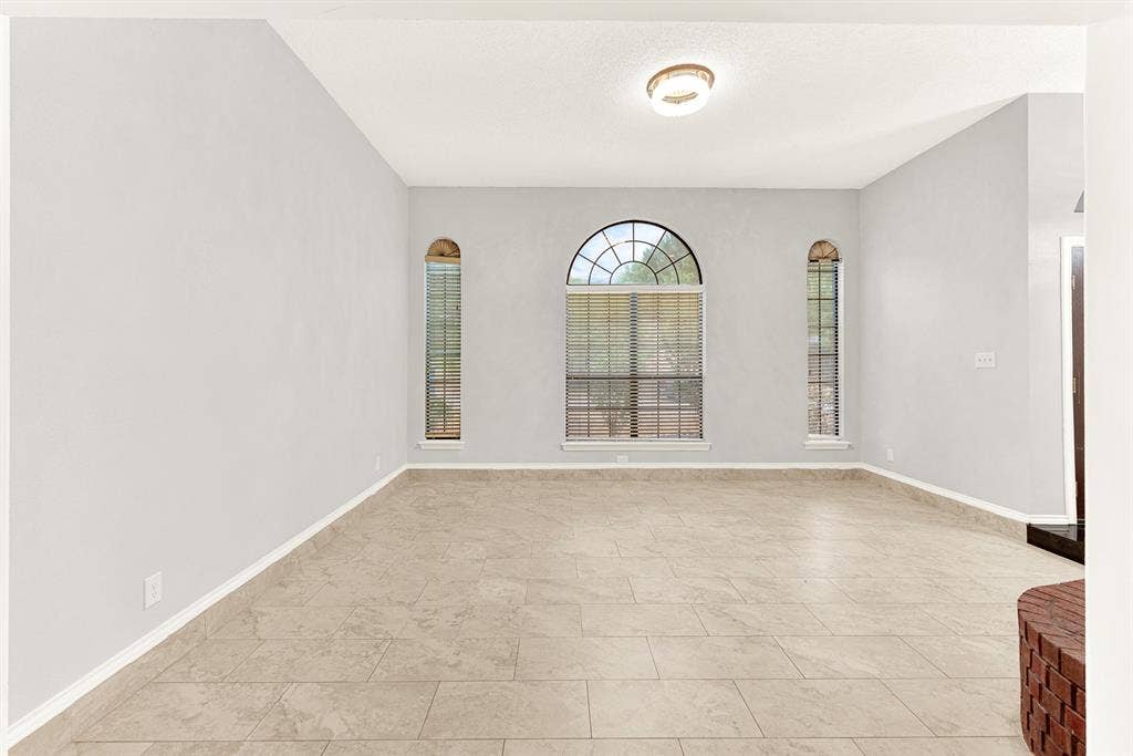 Symmetrical arched windows frame the back wall, creating a serene focal point that draws your eyes outward. Unwind here after a long day, watching the evening shadows softly lengthen across the quiet room