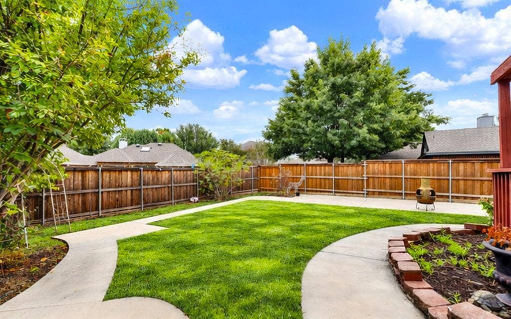 *digitally enhanced*  Sweeping concrete pathways curve smoothly around central lawn space and stone retaining borders. You can easily picture kids or pets playing freely in the fully fenced yard on bright afternoon days.