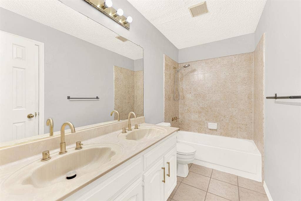 Warm neutral tilework wraps around a built-in tub and shower, complemented by a wide double-sink vanity. You can easily envision your guests enjoying a refreshing, hotel-like morning routine in complete comfort.