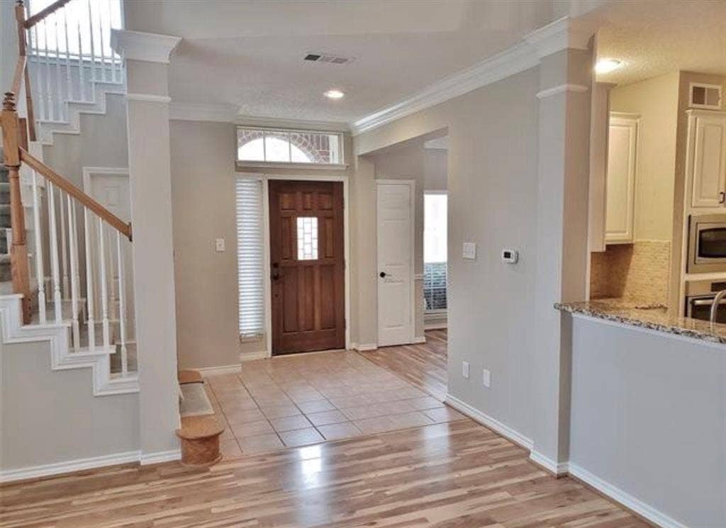 211 Moss Hill Road, Irving, TX 75063 Wood-finish flooring, staircase with wood handrail, tiled entry, wood-paneled door with glass insert, and granite countertops