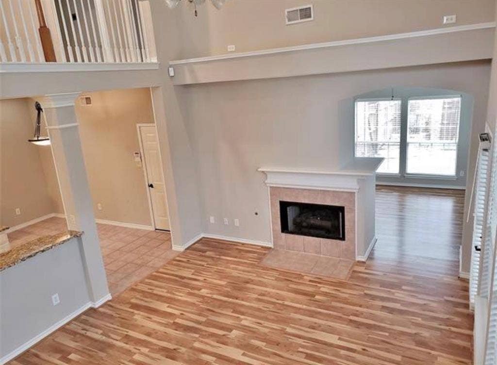 211 Moss Hill Road, Irving, TX 75063 Living area featuring wood-finish flooring, a tiled fireplace with mantel, and large windows