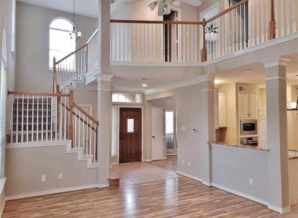 211 Moss Hill Road, Irving, TX 75063 Two-story foyer with wood-finish flooring, grand staircase with wood railing, and an arched transom window