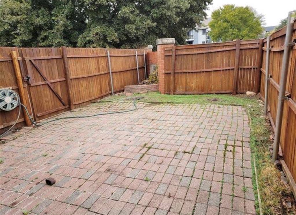 211 Moss Hill Road, Irving, TX 75063 Enclosed backyard featuring a paver patio surface, wood panel fencing, and a side gate