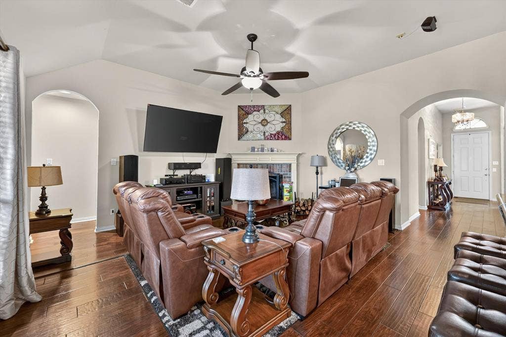 902 Nikki Drive, Cedar Hill, TX 75104 Vaulted ceiling with a ceiling fan, arched doorways, fireplace with mantel, and wood-finish flooring